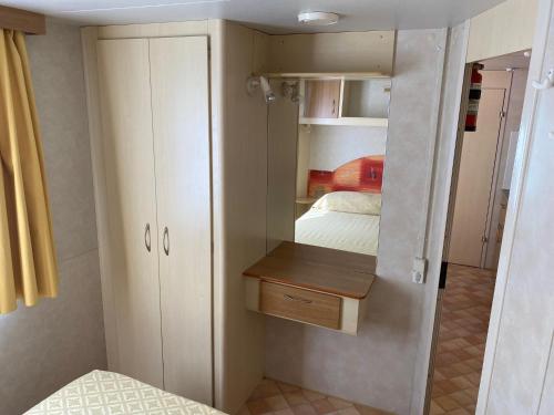 um pequeno quarto com uma cama e um pequeno armário em Mobilehomes Lido di Dante em Lido di Dante