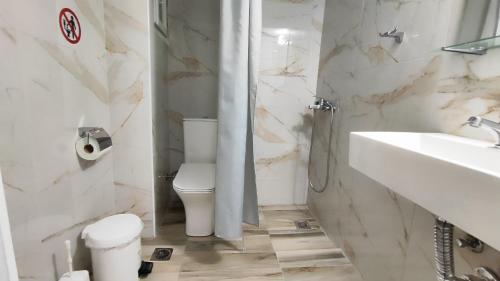 Baño blanco con aseo y lavamanos en Economy apartment, en Flogita