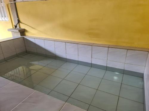 a room with a tiled floor and a yellow wall at Aqiza Home Kuala Krai in Kuala Kerai