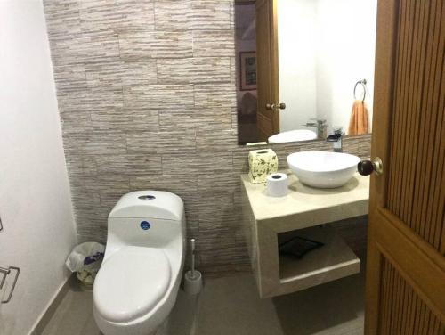 La salle de bains est pourvue de toilettes blanches et d'un lavabo. dans l'établissement El Encanto Beach House, à Santa Marta