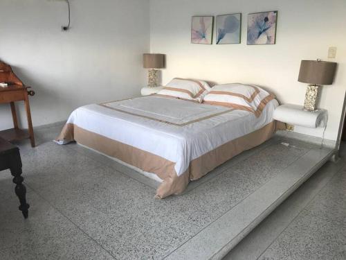 - une chambre avec un lit avec deux lampes et un piano dans l'établissement El Encanto Beach House, à Santa Marta