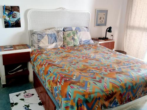 a bedroom with a bed with a colorful comforter at Los Pinos condominio piso 2 in Zorritos