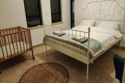 een slaapkamer met een wit bed en een wieg bij וילה חלום יעקב- וילה מקסימה בחצור הגלילת in Hatzor haglilit