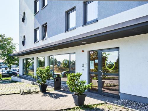 a building with glass doors and potted plants in front at B&B Hotel Mainz-Hechtsheim in Mainz