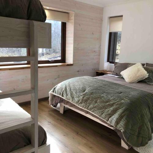 a bedroom with a bunk bed and two windows at Refugio entre Montañas - Malalcahuello in Malalcahuello