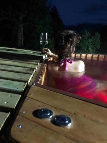 a girl in a bath tub holding a glass of wine at Refugio entre Montañas - Malalcahuello in Malalcahuello