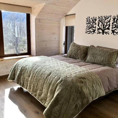 a bedroom with a large bed and a large window at Refugio entre Montañas - Malalcahuello in Malalcahuello
