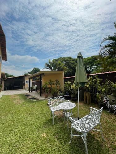 a patio with a table and a green umbrella at Espaço Vitória Imperial in Guapimirim