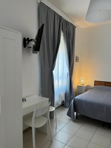 a bedroom with a bed and a desk and a window at B&B Sorgente 23 in Salerno