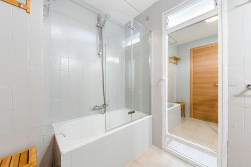 a white bathroom with a tub and a shower at Apartament z widokiem na morze 250 m od plaży in Torrevieja