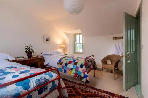 a bedroom with two beds and a desk and a chair at Kenmare Pier Cottage in Kenmare