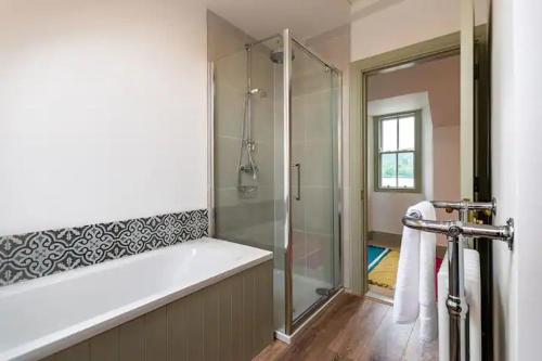 a bathroom with a shower and a tub with a glass door at Kenmare Pier Cottage in Kenmare