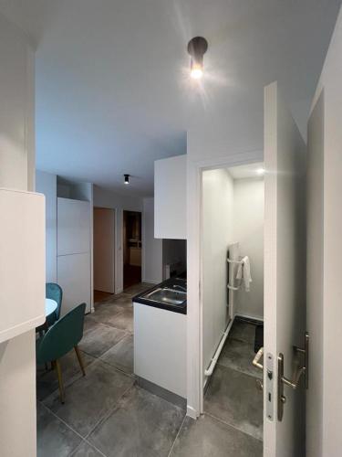 eine Küche mit weißen Schränken und einem Tisch im Zimmer in der Unterkunft Spacieux appartement Paris/Stade De France/CDG in La Courneuve