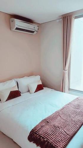 1 dormitorio con cama con almohadas y ventana en 京都Kyoto Home 2BR - 53 Sqm at Downtown Semarang en Semarang