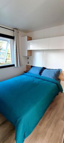 - un grand lit bleu dans une chambre avec fenêtre dans l'établissement Mobil-home - Camping SIBLU Bonne Anse Plage, aux Mathes
