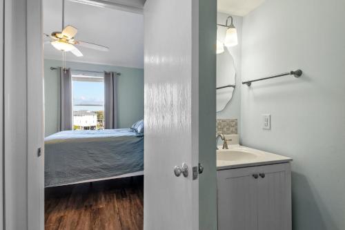 um quarto com uma cama e uma casa de banho com um lavatório em OceanScape- Beach, Pool, and Sun near the heart of Surf City! em Surf City