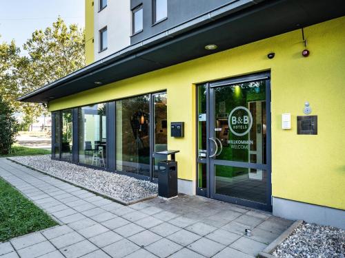 un bâtiment jaune avec un panneau sur la porte dans l'établissement B&B Hotel Freiburg-Süd, à Fribourg-en-Brisgau