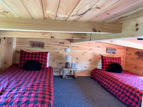 two beds in a room with wooden walls at Beaver Dam Mountain Cabins in Travelers Rest