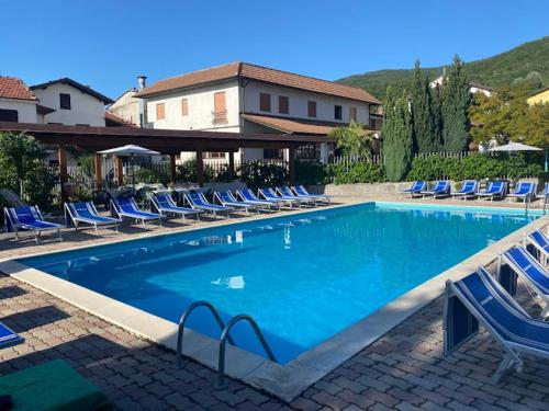 uma grande piscina com cadeiras azuis e uma casa em Casa Vicino em Cantalupo Ligure