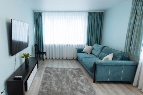 a living room with a blue couch in front of a window at Blue Laguun Apartments in Narva