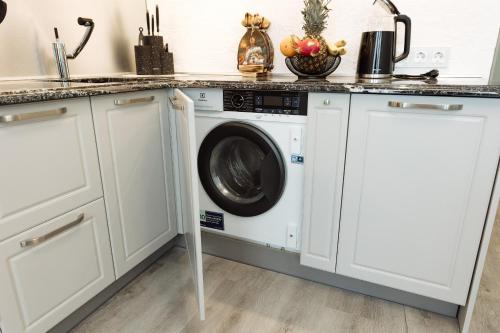 a washing machine in a kitchen with white cabinets at Blue Laguun Apartments in Narva