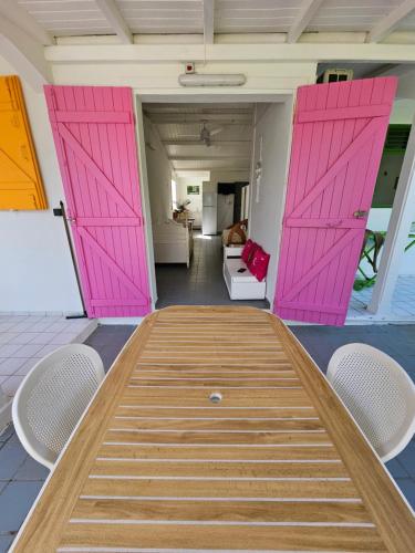 una mesa con puertas rosas en una habitación con sillas en Au paradis créole, en Le Moule