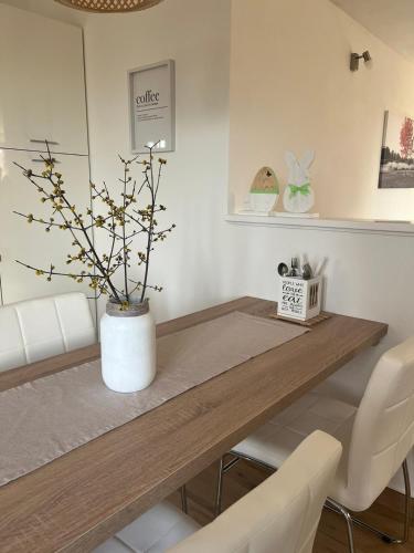 a dining room table with a white vase with a tree at Studio Apartman Nika in Višnjan