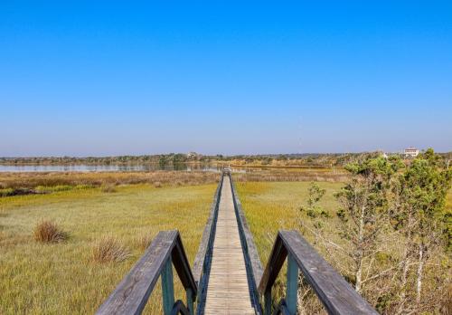 a wooden boardwalk in a field with a bridge at Comfort and Sun at Tranquility Cay in North Topsail Beach