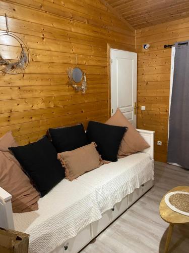 a bed in a room with a wooden wall at Chalet 6 Personnes au calme dans les landes-Mimizan in Bias