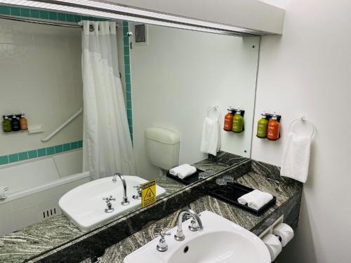 a bathroom with a sink and a toilet and a mirror at Holiday Inn Parramatta by IHG in Sydney