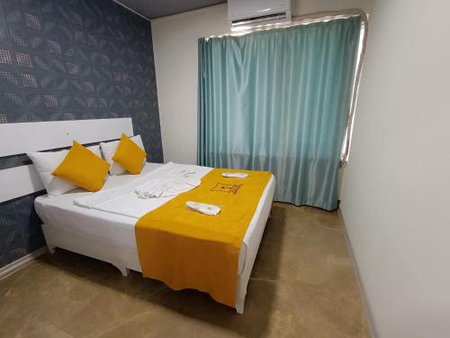 a bedroom with a bed with a yellow blanket on it at Comfy Otel Antalya Lara in Antalya