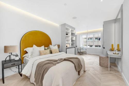 a bedroom with a large bed with a yellow headboard at Arcore Premium Apartments Regent Park in London