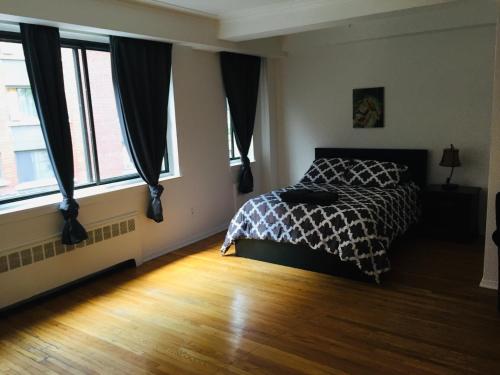 een slaapkamer met een bed in een kamer met ramen bij Stylish Montreal Apartment: Comfortable Stay in the Golden Square Mile in Montreal