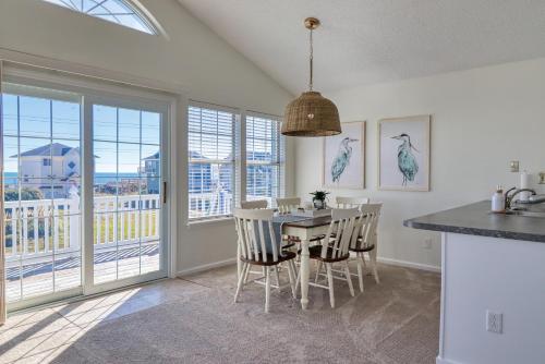 a dining room with a table and chairs and windows at Comfort and Sun at Tranquility Cay in North Topsail Beach