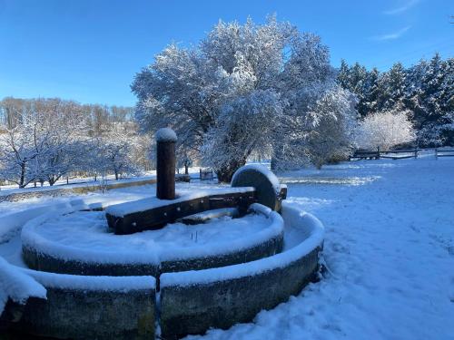 a park covered in snow with trees and benches at Maison La folie douce in Saint-Pierre-de-Manneville