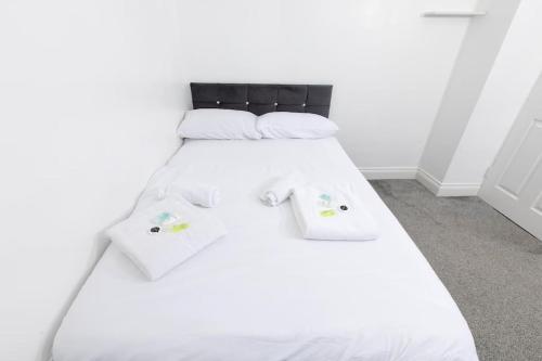 Cama blanca con sábanas y almohadas blancas en Comfy 2 Bedroom House for 4 en Strood