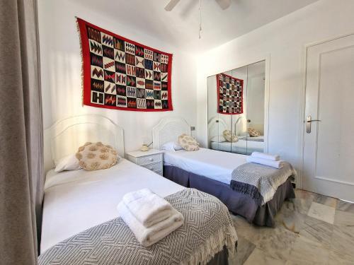 a bedroom with two beds and a mirror at Hermoso Piso en La Cala de Mijas con vistas al mar in La Cala de Mijas