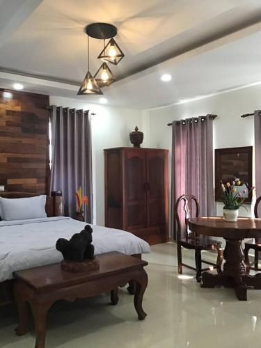 1 dormitorio con cama, mesa y sidra de mesa en Liza Boutique en Phumĭ Ta Phŭl