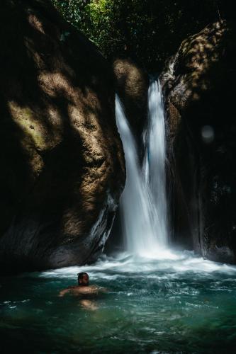 a person in the water in front of a waterfall at ACHIOTÉ Architectural Gem - Adults Only in Uvita