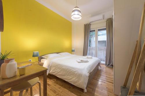 - une chambre avec un lit blanc et un mur jaune dans l'établissement Arktinou apartment, à Athènes