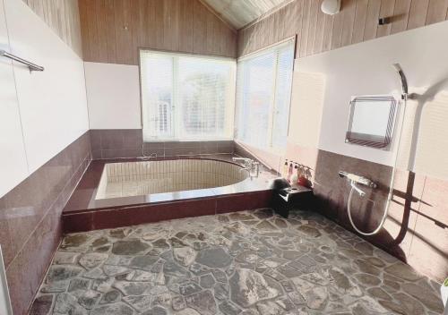 a large bathroom with a tub and a window at 雨でも炭でBBQが出来る/プール付き!MAX12名/駐車2台可能! in Shirahama