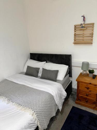 a bed with a black headboard next to a wooden table at P&S rooms guesthouse Lincoln city centre in Lincolnshire