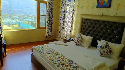 a bedroom with a bed with a large window at Hotel River View Resort in Pahalgām