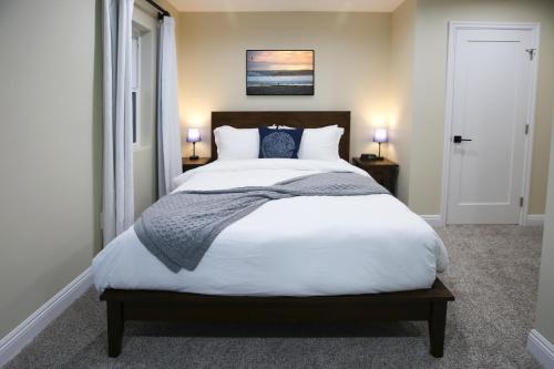 a bedroom with a large bed with white sheets and blue pillows at Luxury Beach Home - Steps to the Sand, Game Room, Firepit, Deck in Oxnard