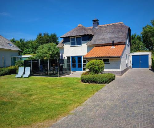 a white house with an orange roof and a yard at Duinvilla Wetterwille in Makkum