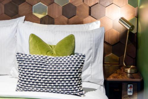 a bed with a pillow and a lamp on a table at The Hive, Central Ludlow, Free Parking, Boutique Hotel Style in Ludlow