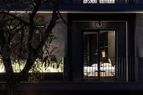 a person sitting on a bed outside a window at The Modernist Athens in Athens