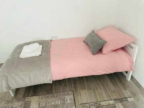a bed with pink and grey sheets and pillows at Apartment Zara Bihac in Bihać