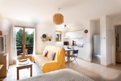un salon avec un canapé jaune et une cuisine dans l'établissement À Laye station Charmant T1 33 m2, à Laye
