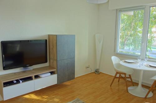 een woonkamer met een tv en een tafel met stoelen bij Arbres & Tennis in Straatsburg